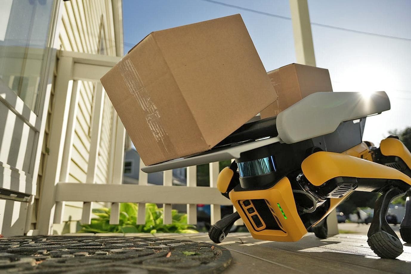 Boston Dynamics’ robot Spot lowers itself on a porch as it unloads cardboard boxes.