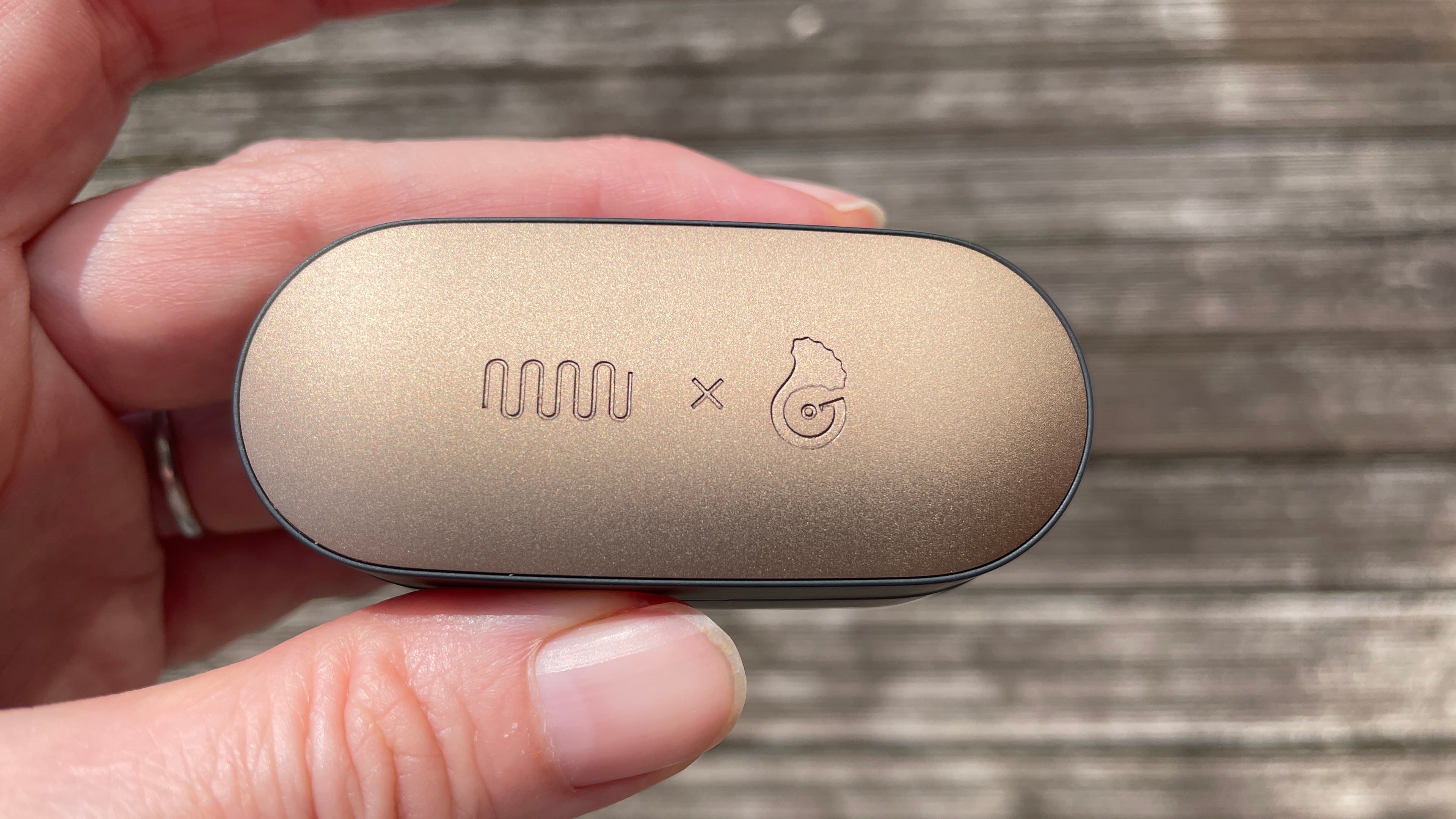 Status Audio Pro X GoldenSound, next to AirPods or held in a hand, with gold accents showing
