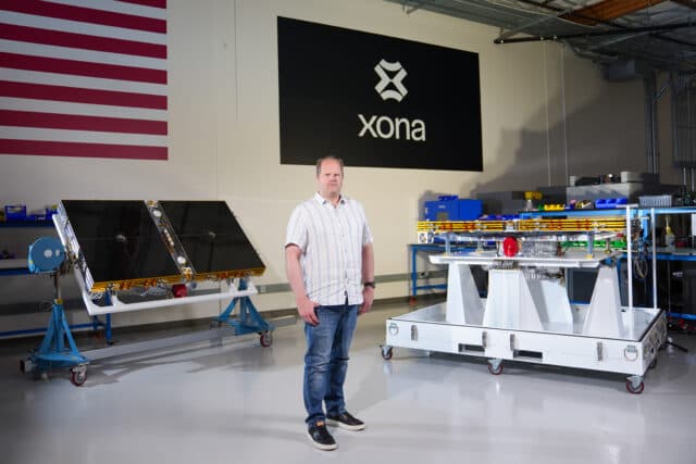 A view of the Xona Space Systems satellite factory in Burlingame, California. The foreground shows a signpost with signs pointing toward "propulsion unit," "guidance & navigation," and "thermal testing."