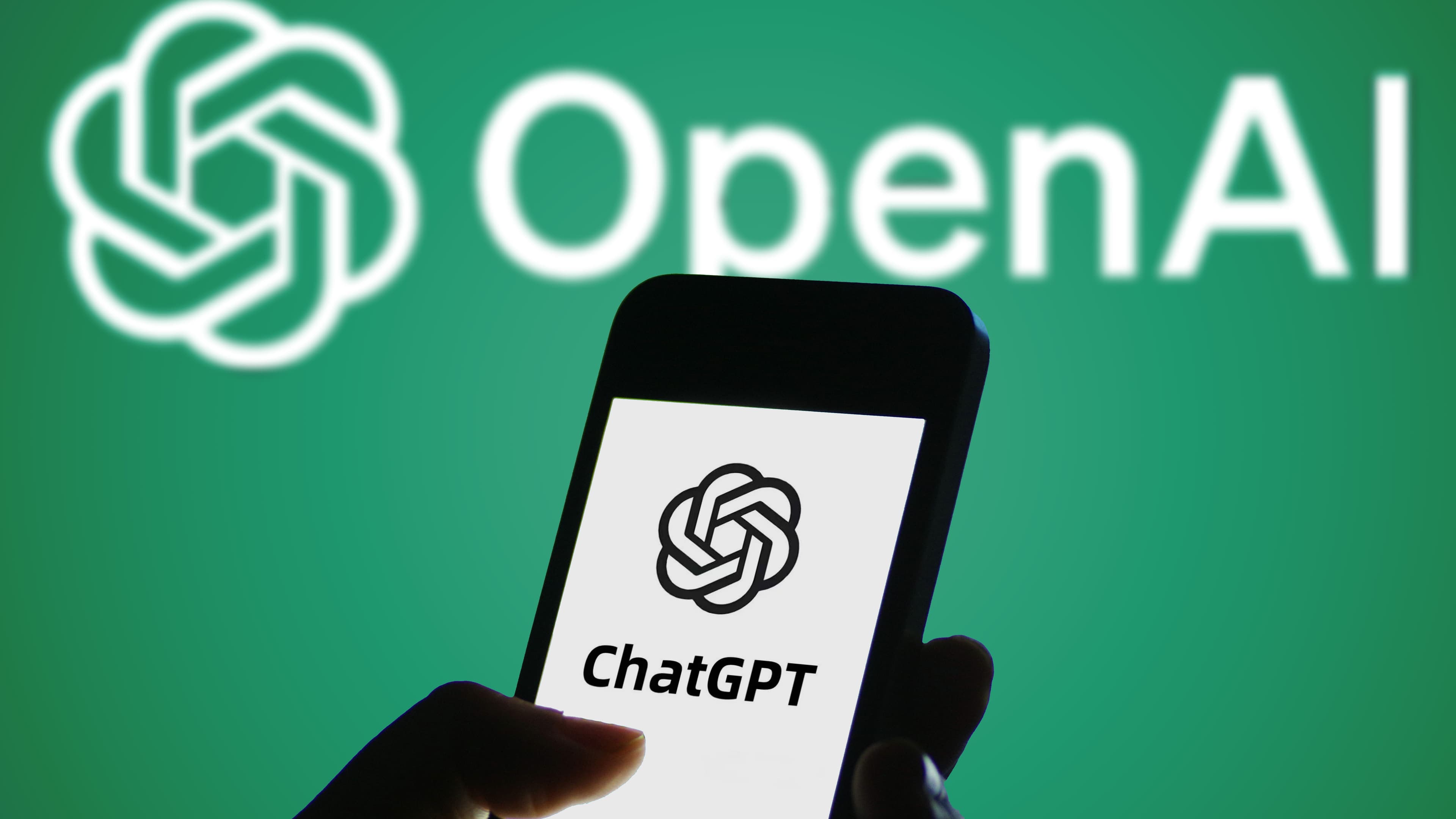 Logotipo de ChatGPT mostrado en la pantalla de un teléfono inteligente con un logotipo de OpenAI al fondo
