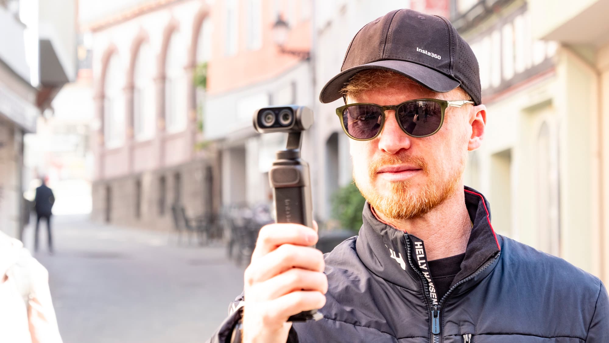 Hombre sosteniendo la cámara de vlogs Insta360 Luna Ultra en un día soleado en un casco antiguo