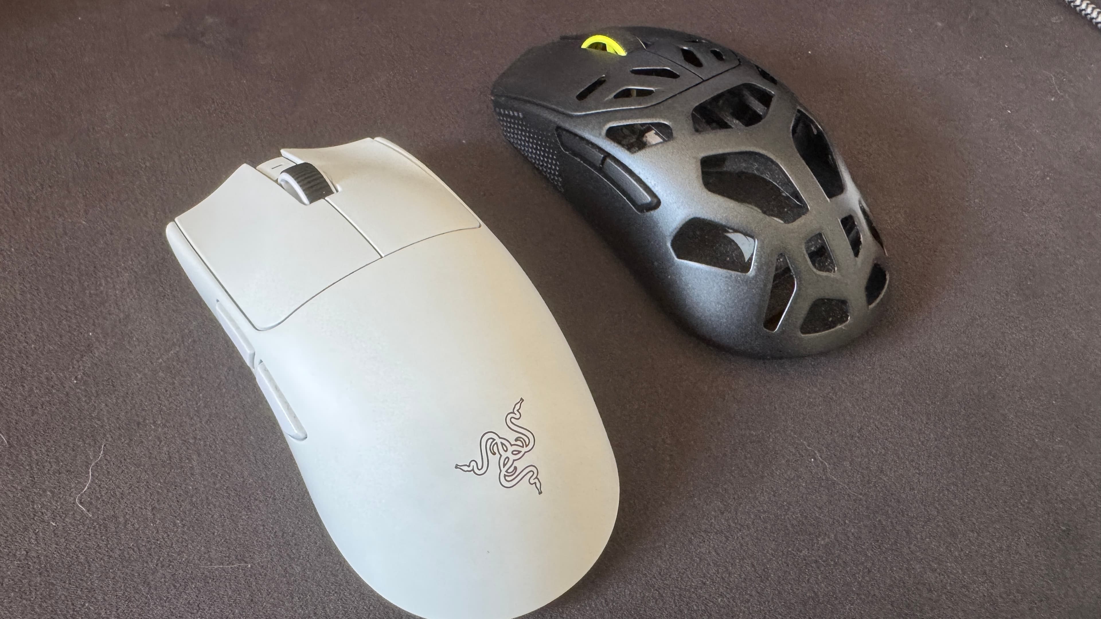 Two gaming mice next to each other on a black mousepad